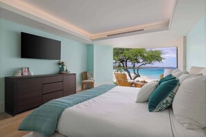 A bedroom with a bed, a TV, a dresser, a chair, and a view of the beach. - Hapuna Beach Residences B31 Three Bedroom (Kamuela)