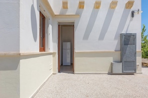 Un bĂątiment Ă lâextĂ©rieur blanc, avec une porte donnant sur une petite piĂšce et une unitĂ© de ventilation.