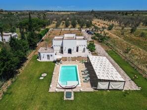 Une grande maison avec une piscine, un patio couvert et une cour clôturée.