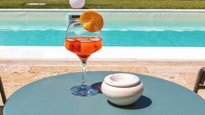 A glass with a slice of orange on a table by a pool. - Villa Calliope by Perle di Puglia (Cutrofiano)