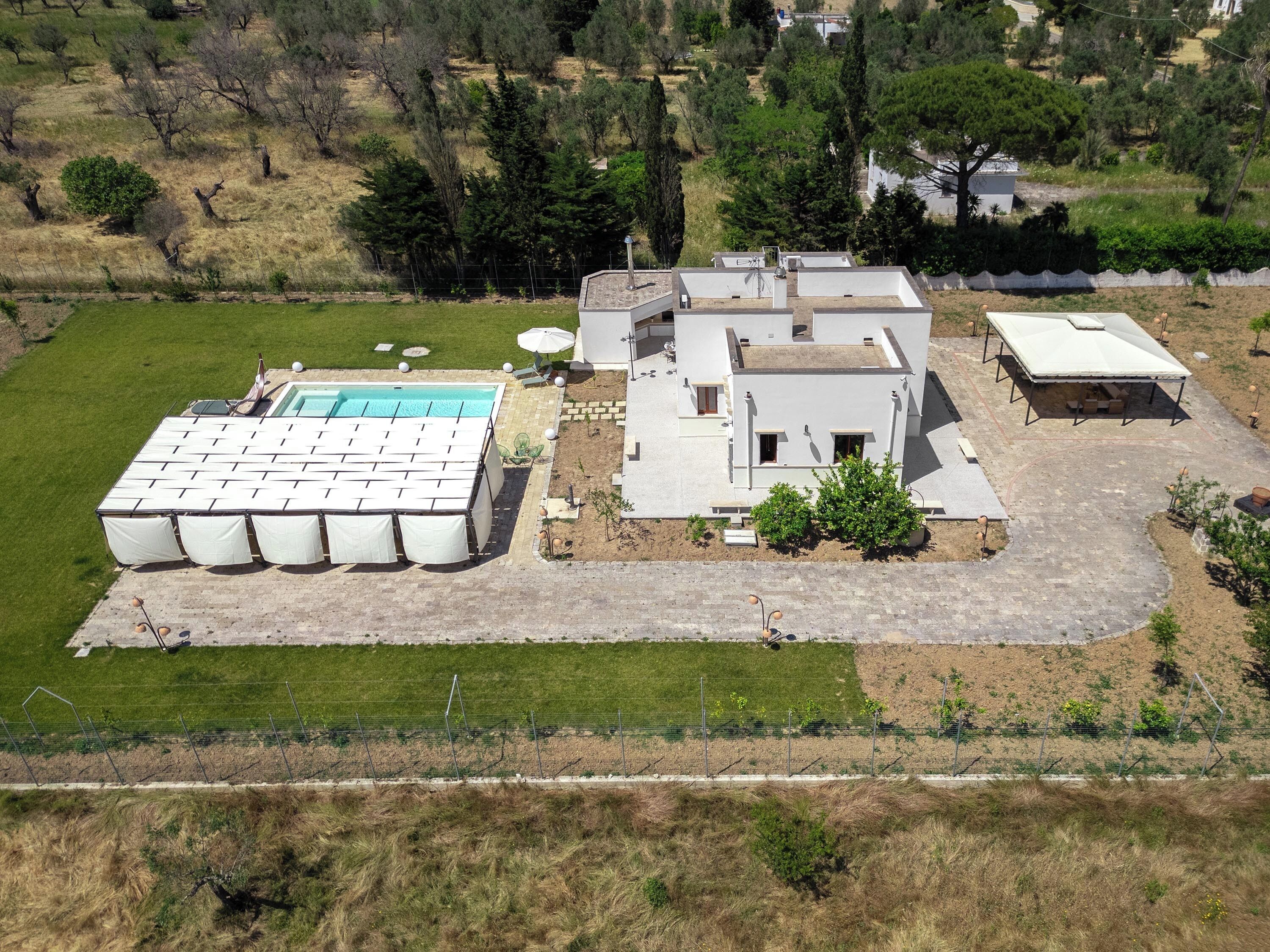 A modern house with a swimming pool, a covered patio, and a fenced garden.