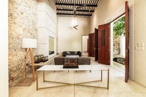 Ein modernes Interieur mit einer Steinwand, einem Tisch mit Glasplatte, einer Couch und einem Deckenventilator.