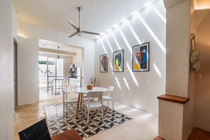 Ein modernes Interieur mit Essbereich, Deckenventilator, abstrakten Wandbildern und einer Treppe.