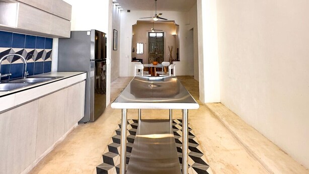 A modern kitchen with a central island, stainless steel appliances, and a geometric patterned floor. - Private Pool • Minimal Design • Quiet Stay (Merida)