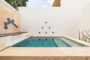 Ein Schwimmbecken mit einer gefliesten Wand und einem geometrischen Muster auf der linken Seite.