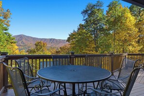 Eine Terrasse mit rundem Tisch und Stühlen mit Blick auf eine gebirgige Landschaft im Herbstlaub.