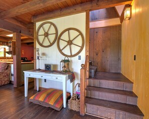 A wooden interior with a staircase, a white table with drawers, and two large wooden wheels on the wall. - Red Nova - Cabin in Pastoral Setting, Canton NC (Canton)