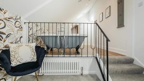 A staircase leading to a bathroom with a bathtub, a radiator, and a chair. - greenhead hotel (Greenhead)