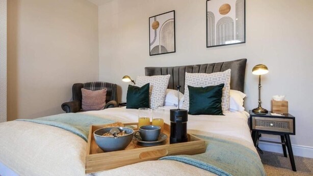A hotel room with a bed, bedside tables, a tray with breakfast items, and artwork on the walls. - greenhead hotel (Greenhead)