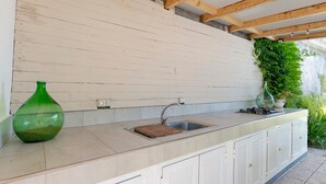 A kitchen with a sink, a green vase, and cabinets. - Iris Holiday Home in Stellanello: Your Peaceful Retreat in Liguria (Rossi)