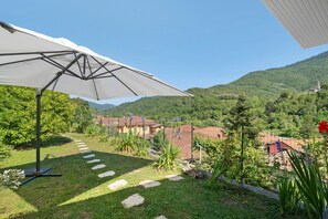 Ein Garten mit Sonnenschirm, Steintreppe und Blick auf Häuser im Hintergrund.