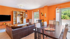 A living room with a sofa, dining table, and TV. - Iris Holiday Home in Stellanello: Your Peaceful Retreat in Liguria (Rossi)