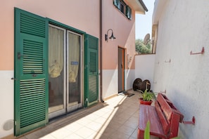 A narrow corridor with a sliding glass door, a bench, and a potted plant.