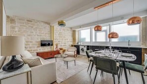 Een moderne woonkamer met een stenen muur, een bank, een salontafel en een eethoek met een tafel gedekt voor vier personen.