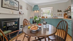 Un comedor con una mesa preparada para el desayuno, una chimenea, armarios color turquesa y un ventanal con vistas.
