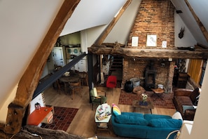 A loft-style living area with exposed wooden beams, a brick fireplace, and a cozy seating arrangement. - SPACIOUS COTTAGE BETWEEN LAND AND SEA - Sleeps 9, 5 bedrooms, 2 shower rooms, 3 toilets, ping-pong table (Veulettes-sur-Mer)