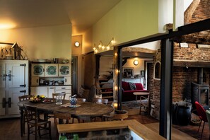 A rustic kitchen with wooden furniture, a dining table, and a brick fireplace. - SPACIOUS COTTAGE BETWEEN LAND AND SEA - Sleeps 9, 5 bedrooms, 2 shower rooms, 3 toilets, ping-pong table (Veulettes-sur-Mer)