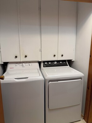 Une buanderie équipée de deux appareils électroménagers blancs, dont l’un est doté d’un panneau de commande et l’autre d’une porte.
