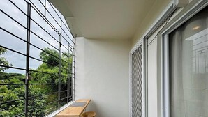 Uma varanda com vista para o verde, uma mesa de madeira e uma parede estampada.