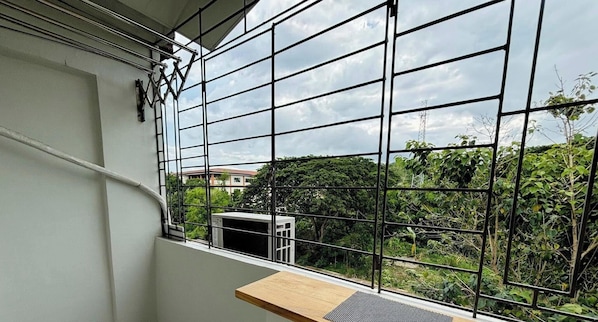 A balcony with a metal railing, a small wooden table, and an air conditioning unit. - Cozy Pet-friendly Studio Condo in Cagayan de Oro (Cagayan de Oro)