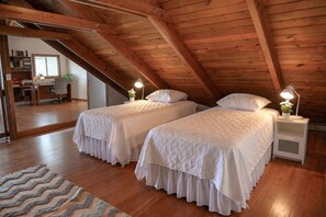 A bedroom with two beds, wooden ceiling beams, a desk with a chair, and a window. - New Mountain Escape Panoramic San Juan Views (Aguas Buenas)