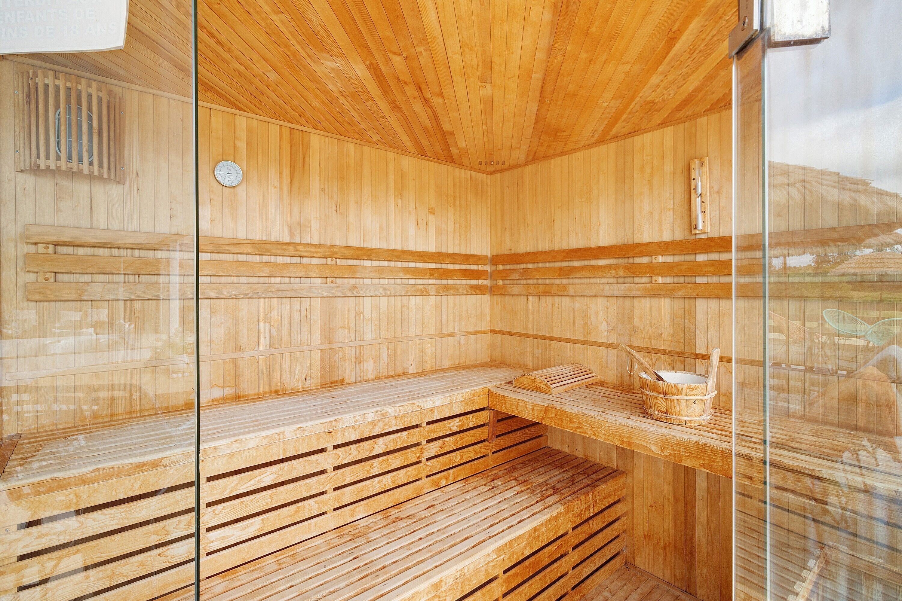 Een sauna met houten banken en een glazen scheiding.