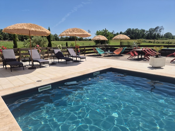 A pool area with lounge chairs, umbrellas, and a view of the surrounding landscape.