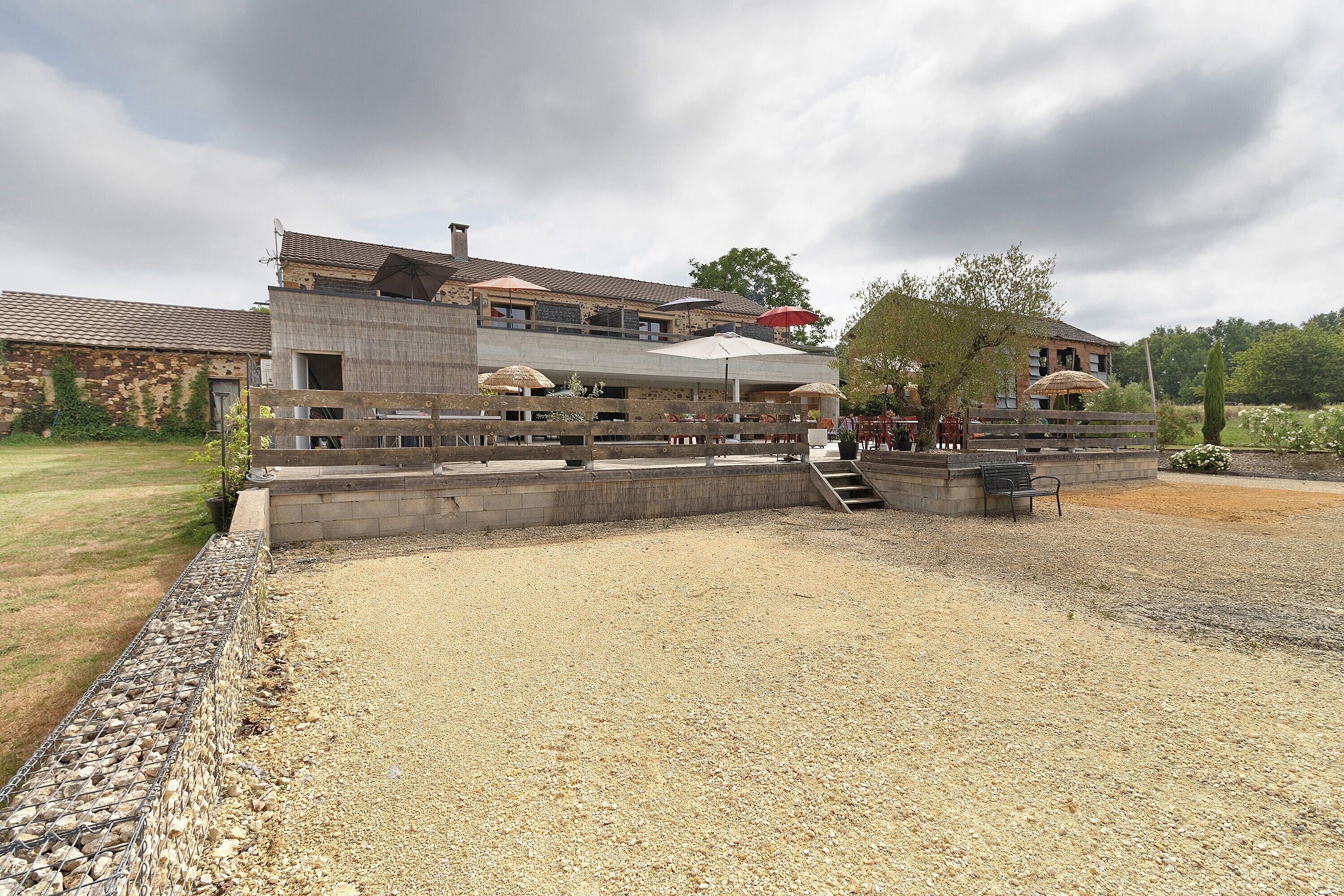 A building with a stone facade, outdoor seating area, and a gravel courtyard.