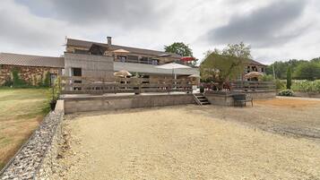A building with a stone facade, outdoor seating area, and a gravel courtyard.