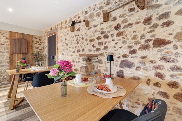 A dining area with a stone wall, wooden furniture, and a vase with flowers.