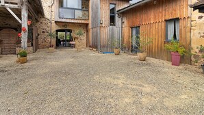 Un edificio rústico con un patio de grava, fachada de madera y plantas en macetas.