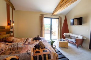 A bedroom with a bed, a wooden headboard, a television, a sliding glass door, and a vintage bathtub.