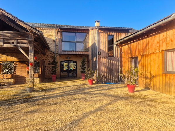 A rustic building with a stone facade, wooden exterior, and a central entrance with a door and windows.