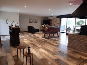 Un vaste espace de vie doté d’un plancher en bois, d’un canapé, d’une table basse et d’un téléviseur.
