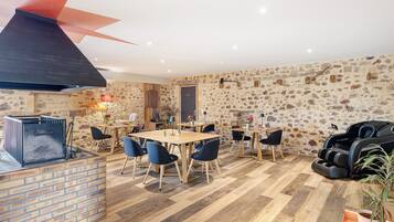 Un espace repas agrémenté d’un mur en pierre, d’un comptoir en briques et d’un fauteuil de massage.