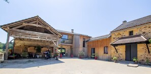 A rustic building with a covered outdoor area, a motorcycle, and potted plants.