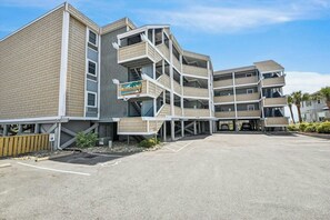 Ein mehrstöckiges Hotel mit modernem Design, inklusive Balkonen und einem Parkplatz.