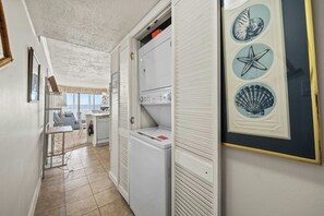 Ein Waschraum mit Waschmaschine, Trockner und einem Kunstwerk mit Strandmotiv.