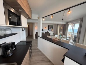 A modern kitchen with a coffee maker, a microwave, and a dining area with a view of the sea. - Exclusive Oceanfront Apartment in Fuengirola, Recently Renovated (Fuengirola)