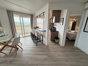 A modern hotel room with a dining area, kitchenette, and a balcony with a view. - Exclusive Oceanfront Apartment in Fuengirola, Recently Renovated (Fuengirola)