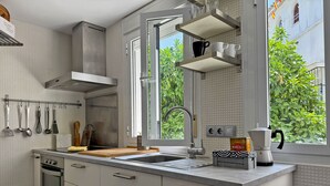 Une cuisine moderne avec une fenêtre, une machine à café et des ustensiles de cuisine accrochés au mur.