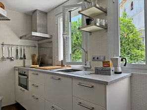 Eine moderne Küche mit Fenster, einer Kaffeemaschine und Geschirr, das an der Wand hängt.