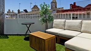 Une terrasse sur le toit avec une table en bois, un canapé et une petite plante.