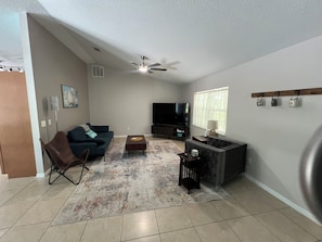 A living room with a sofa, a coffee table, a TV, and a ceiling fan.