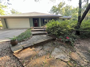 A residential house with a garage, stone steps, and a garden.