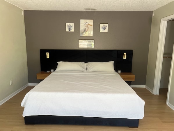 A bedroom with a large bed, two bedside tables, a headboard, and three wall-mounted pictures.