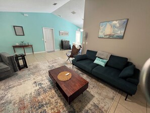 A living room with a dark green sofa, a wooden coffee table, and a patterned rug.