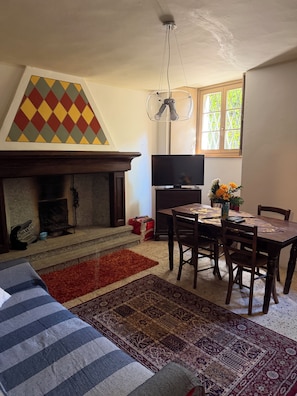 Ein Wohnzimmer mit Kamin, einem Esstisch mit Stühlen, einem Fernseher und einem Fenster mit Aussicht.