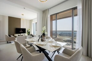 Ein modernes Hotelzimmer mit Essbereich, einem Flachbildfernseher und einem Balkon mit Blick auf die Stadt.