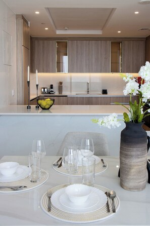 Eine moderne Küche mit Holzschränken, einer Arbeitsplatte und einem Essbereich, gedeckt mit weißem Geschirr und einer Blumenvase.